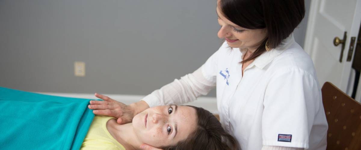 A woman is helping a child with her ear.