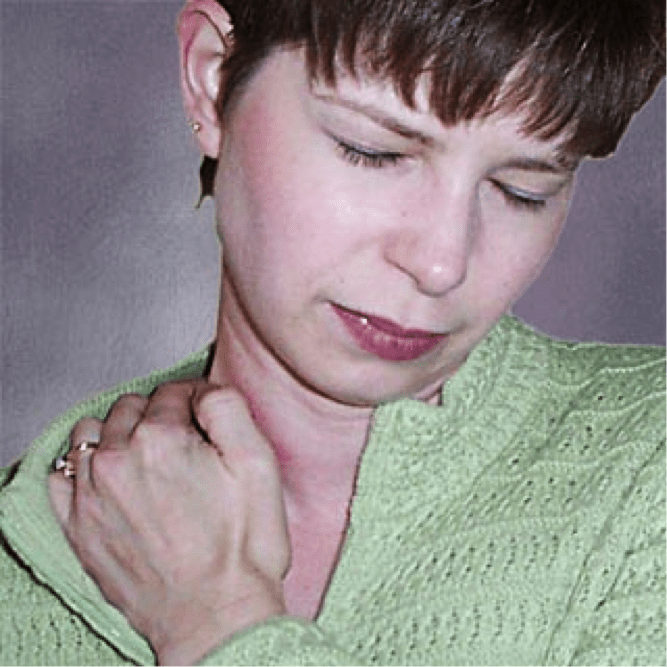 A woman in green sweater holding her neck.